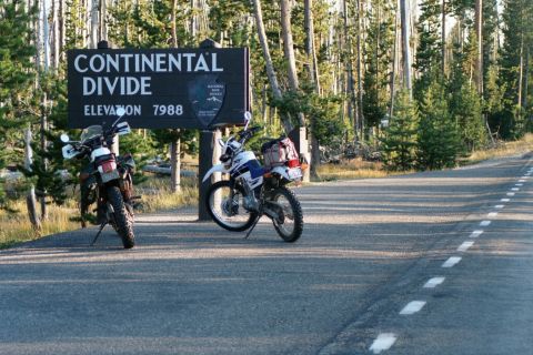 1976 Ford F-150 - Motorcycles stop at the Continental Divide sign, elevation 7988 feet, surrounded by pine trees.