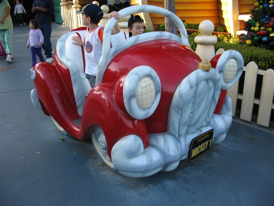 Kids in a red cartoon car with a Mickey 1 license plate