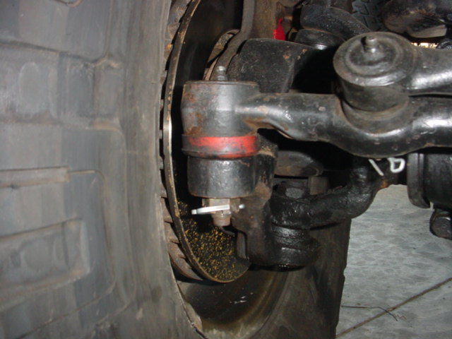 Close-up of a vehicle's steering linkage with a large tire and brake rotor