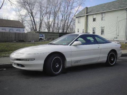 1996 Ford Probe - A white 1996 Ford Probe coupe is parked on the side of the road in front of a house.