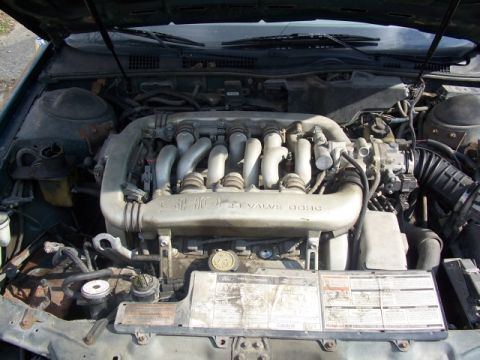 1993 Ford Taurus - The engine bay of a 1993 Ford Taurus is shown, its V6 engine and associated components.