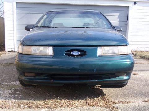 1993 Ford Taurus - Front view of a green 1993 Ford Taurus parked in front of a garage.