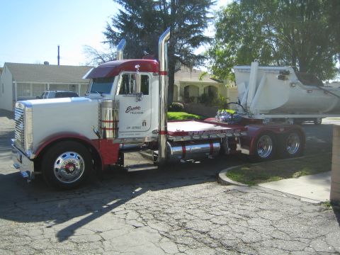 1968 Ford Mustang - Peterbilt semi-truck with a dump trailer is parked on a cracked asphalt surface.