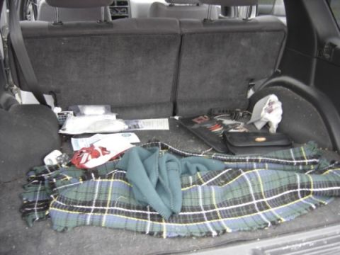 1999 Ford Taurus - The cargo area of a vehicle is shown with a plaid blanket, various bags, and a purse.
