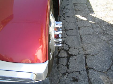 1968 Ford Mustang - Close-up of a red truck's wheel and fender, parked next to a cracked asphalt surface.