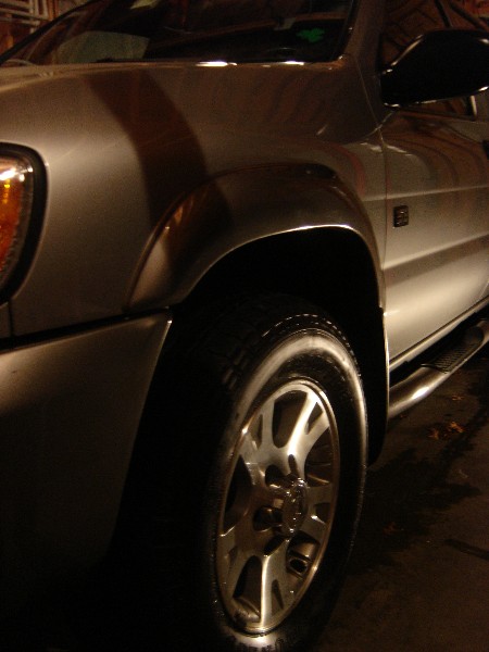 1999 Ford Taurus - Close-up view of a silver SUV's front fender, wheel, and running boards.