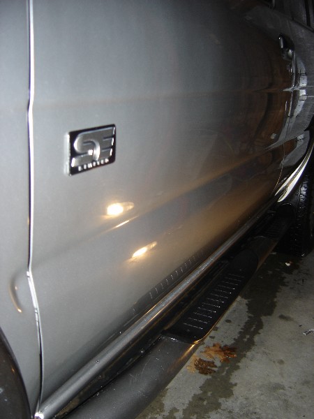 1999 Ford Taurus - Close-up of a silver SUV's side panel, showing a distinctive 'S Limited' badge and a black running board.