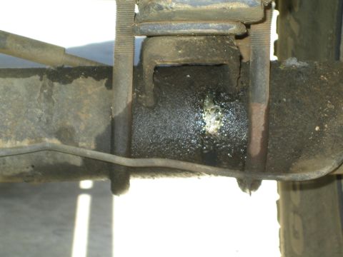 1990 Ford Bronco - Close-up of a welded leaf-spring perch and U-bolt mount on the underside of a vehicle's rear axle.