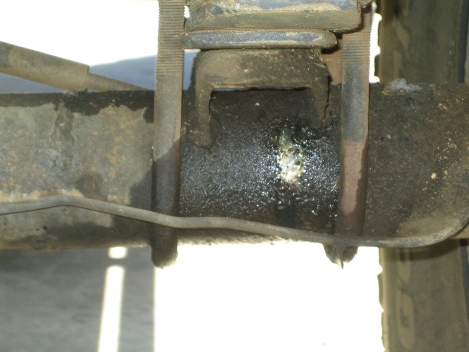 Close-up of welded leaf-spring axle mount under a vehicle chassis