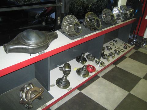 1990 Ford Bronco - display shelf with red trim holds rows of differential housings, third members and gear components above a checkered floor.