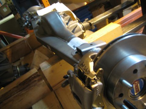 1990 Ford Bronco - Close-up of one end of an axle housing showing the differential, brake caliper and disc rotor on the bench.