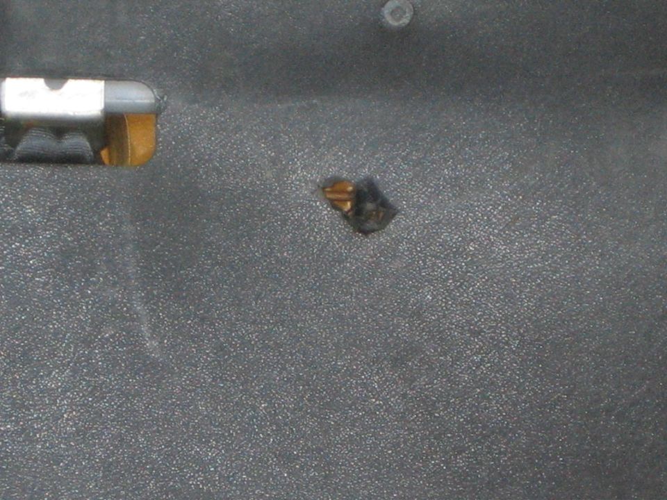 Small chip or damage spot on a textured dark interior panel