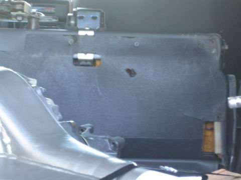 1990 Ford Bronco - Close-up of a dark vehicle interior panel with metal mounting brackets beside a bare polished aluminum body panel.