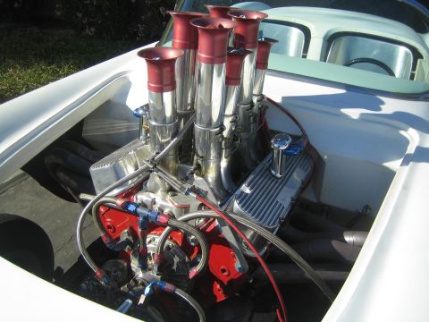 1968 Ford Mustang - The engine bay of a custom car features a powerful V8 engine with prominent chrome velocity stacks.