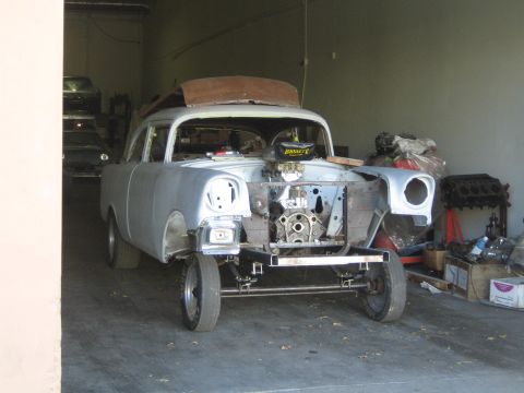 1968 Ford Mustang - A car is in a garage undergoing repairs, with its front end disassembled and engine visible.