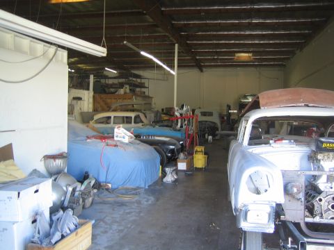 1968 Ford Mustang - Multiple vehicles are present in a workshop, undergoing repairs or restoration.