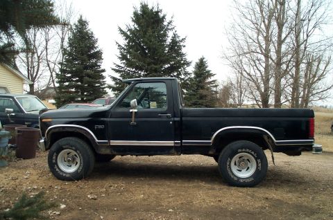 1984 Ford Bronco - Side view of a black pickup truck, likely from the early 1980s, with F-150 badging.