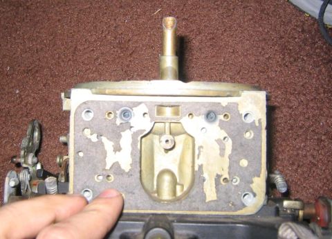 1969 Ford Mustang - A carburetor part is shown in detail, with a finger indicating a specific area on the gasket.