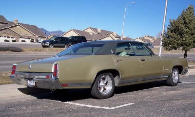 1972 Ford Ranchero - A 1971 Oldsmobile Ninety-Eight sedan is viewed from the rear three-quarter angle in a parking lot.