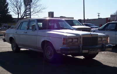 1972 Ford Ranchero - This white sedan, likely a 1979 model, is parked outdoors with other vehicles visible in the background.