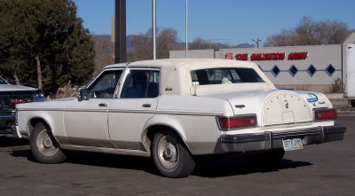 1972 Ford Ranchero - A white sedan with a vinyl top is parked in a lot, with a Salvation Army building visible behind it.