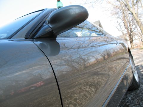 1996 Ford Probe - Side view of a 1996 Ford Probe, with reflections of trees in the car's body.