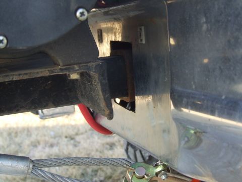 1986 Ford Bronco - Tight low-angle detail of a truck's front frame horn area behind a chrome bumper, showing a rectangular slot cut in the bumper for the fram…