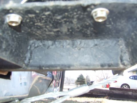 1986 Ford Bronco - Extreme close-up of a black-painted steel frame rail or bumper mount showing a welded-in reinforcement plate with a visible weld bead and t…