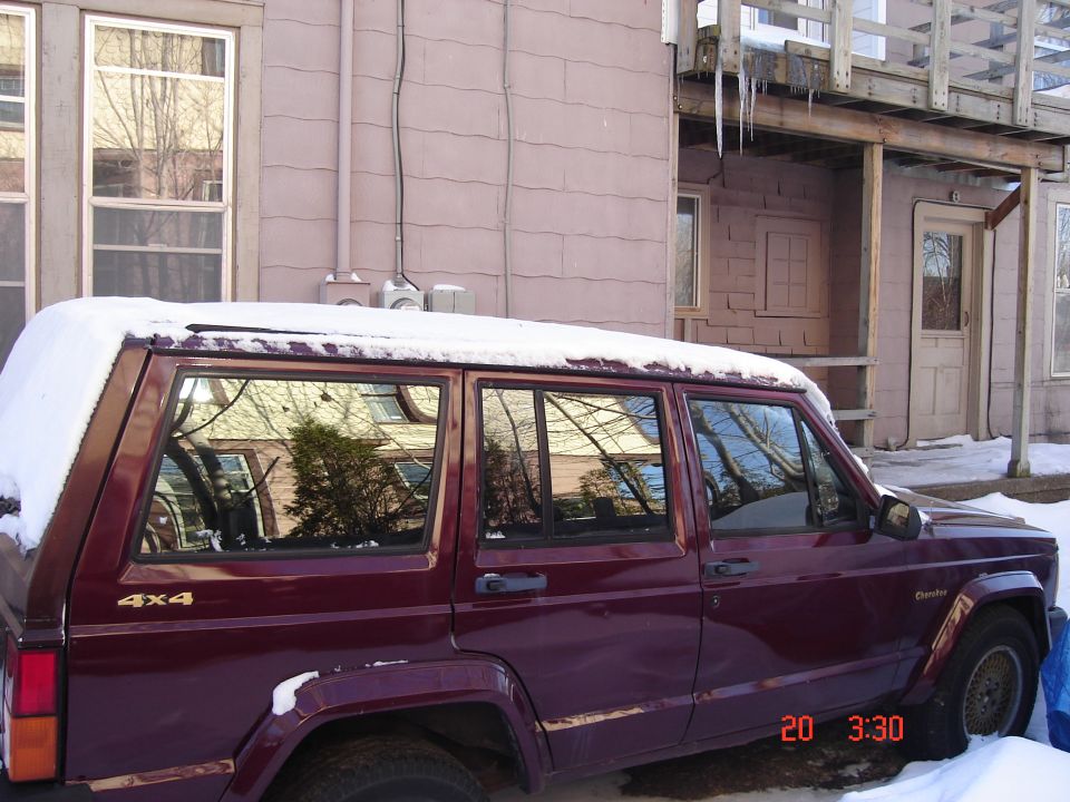 Maroon Jeep Cherokee with snow on roof, side view