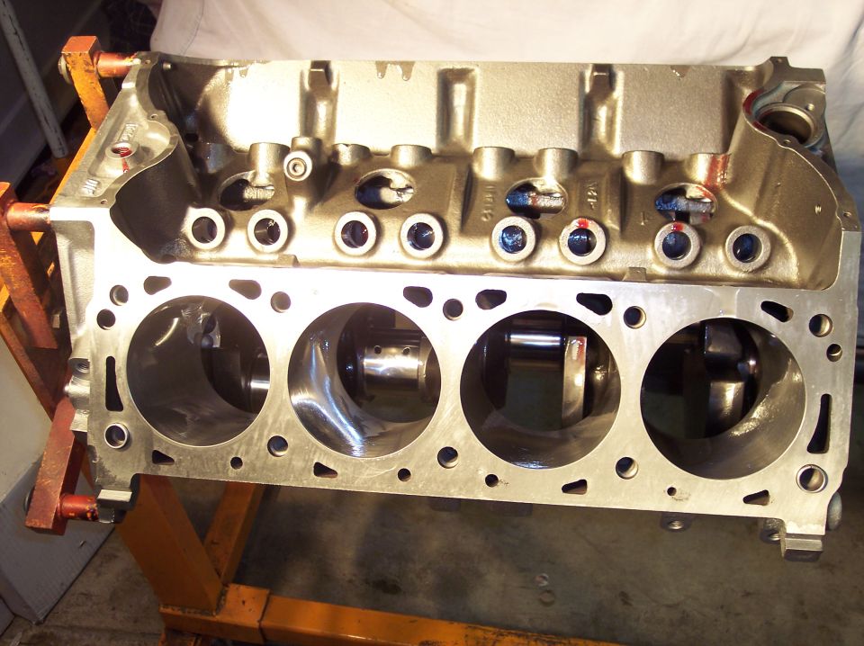 Engine block on an orange stand. Cylinders and crankshaft visible
