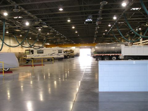 1993 Ford Bronco - Multiple vehicles are parked inside a large industrial garage with overhead lighting and ventilation.