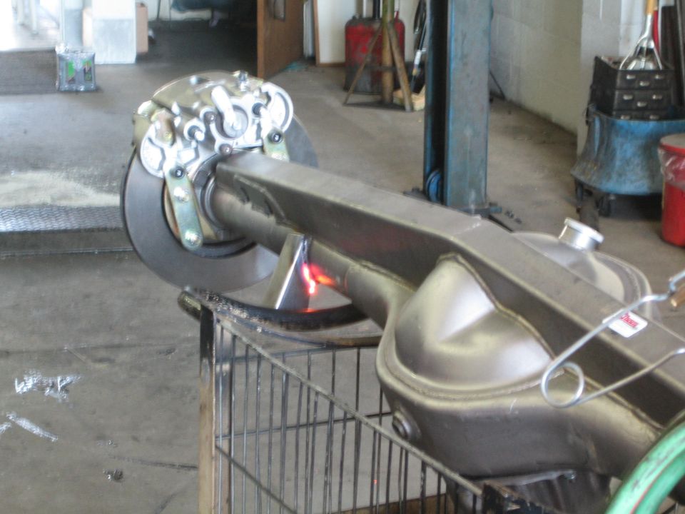 Axle housing with disc-brake hub being heated with a torch flame on a shop cart