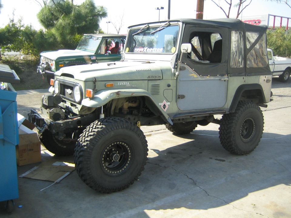 Sage green Toyota Land Cruiser FJ40 with soft top and large off-road tires outdoors