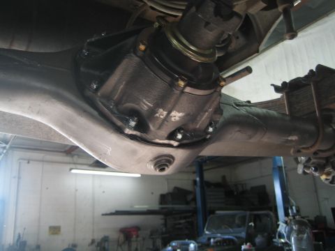 1990 Ford Bronco - close underside view of a differential housing and axle tubes on a vehicle raised on a shop lift.