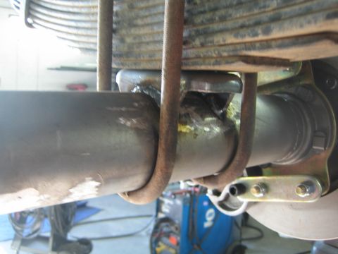 1990 Ford Bronco - close-up of an axle tube with a leaf spring, U-bolts and a fresh weld near the differential, viewed from underneath.