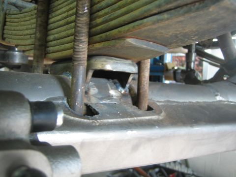 1990 Ford Bronco - close-up from below of a leaf-spring stack with threaded U-bolts and a welded spring perch on an axle housing.