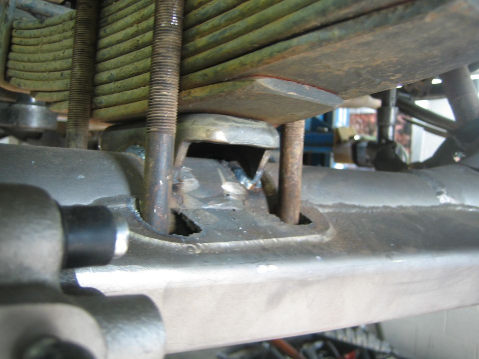 Closeup of leaf spring stack, U-bolts and welded axle perch from below