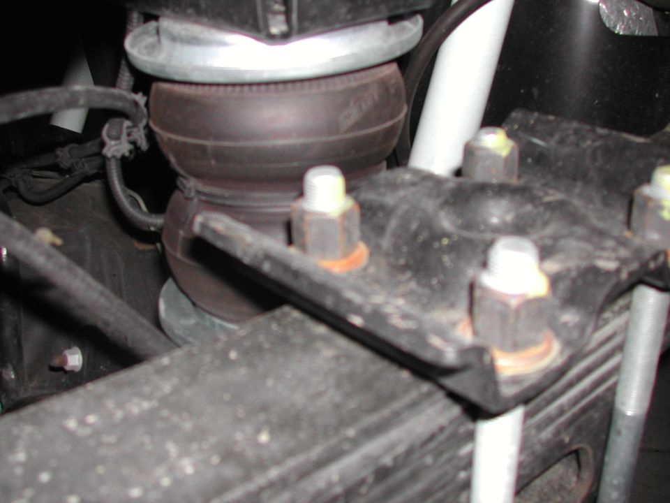 Underside view of an air bag helper spring installed over leaf springs with U-bolts and brackets