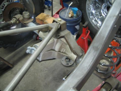 1990 Ford Bronco - close view of a bare-metal tube chassis showing fabricated suspension links, a bracket and a chrome coil spring during a build.