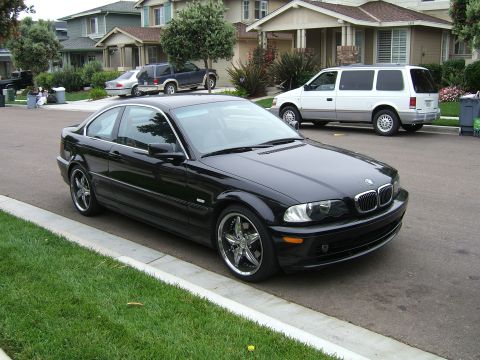2002 BMW 3 Series - A black 2002 BMW 3 Series coupe is parked on a residential street with other vehicles in the background.