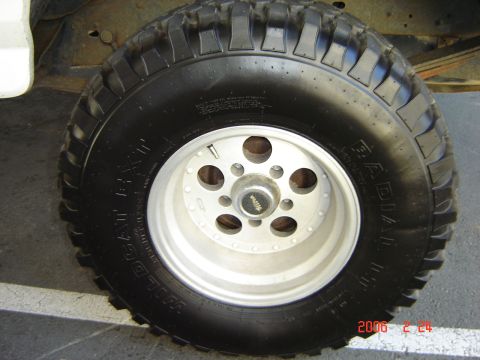 1993 Ford Bronco - A close-up view of a vehicle's tire and wheel assembly, showing off-road tread and a silver alloy rim.