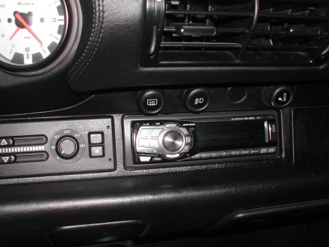 1997 Porsche 911 - Close-up of a car's dashboard, showing the stereo, climate controls, and a gauge.