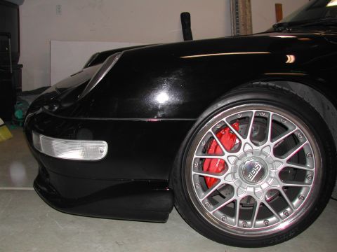 1997 Porsche 911 - Close-up of a black Porsche 911's front wheel and fender, showing custom BBS wheels and red brake calipers.