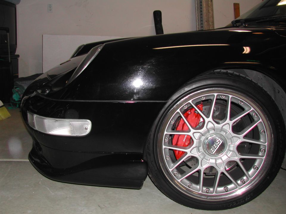 Black Porsche 911 front corner with silver BBS wheel and red Porsche brake caliper