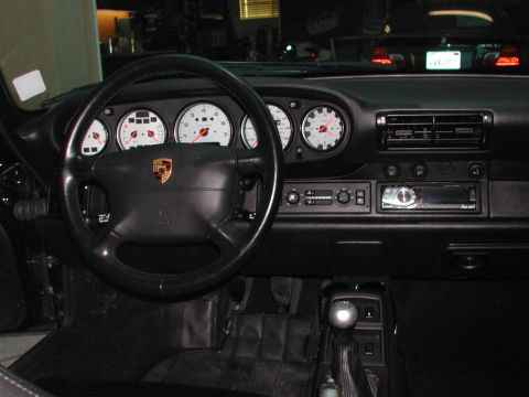 1997 Porsche 911 - The interior of a 1997 Porsche 911 features a classic dashboard layout with prominent gauges and a leather-wrapped steering wheel.