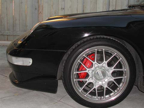 1997 Porsche 911 - Close-up of a black Porsche 911's front wheel, its red brake caliper and BBS rim.