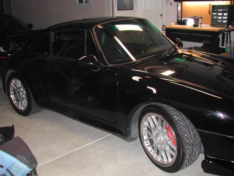 1997 Porsche 911 - A black Porsche 911 is parked in a garage, showing its front three-quarter view.