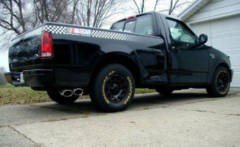 1999 Ford Crown Victoria - This black pickup truck features NASCAR branding along its bed and a dual exhaust system.