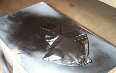 1998 Ford Crown Victoria - A black box and a plastic bag are placed on black paper, possibly for painting.