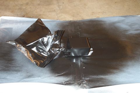 1998 Ford Crown Victoria - A part is being spray painted black on a covered surface, with a watermark at the bottom right.